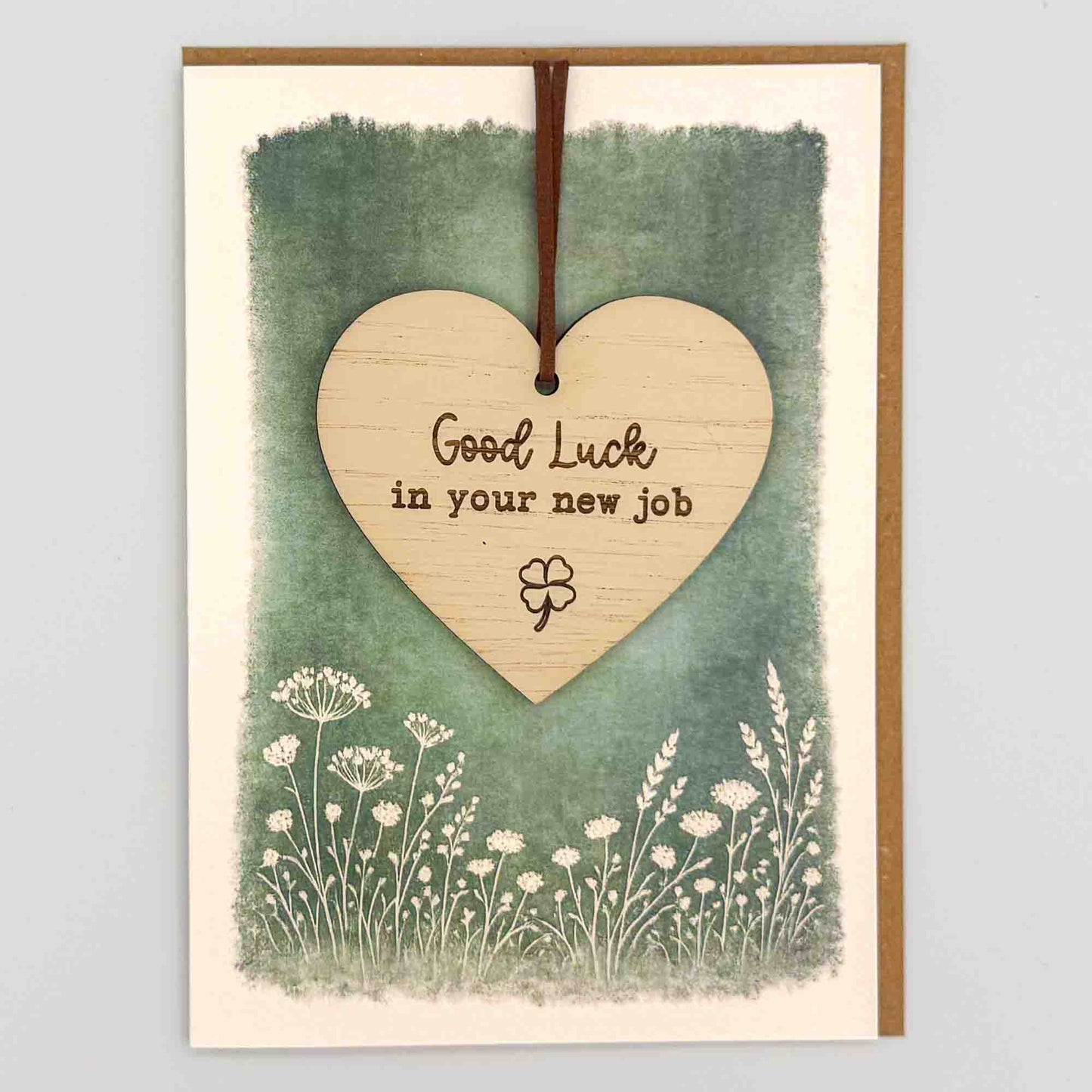 Good luck new job clover heart keepsake card from Sprinkled with Magic, featuring a removable wooden heart keepsake, clover icon, green botanical design and recycled kraft envelope.