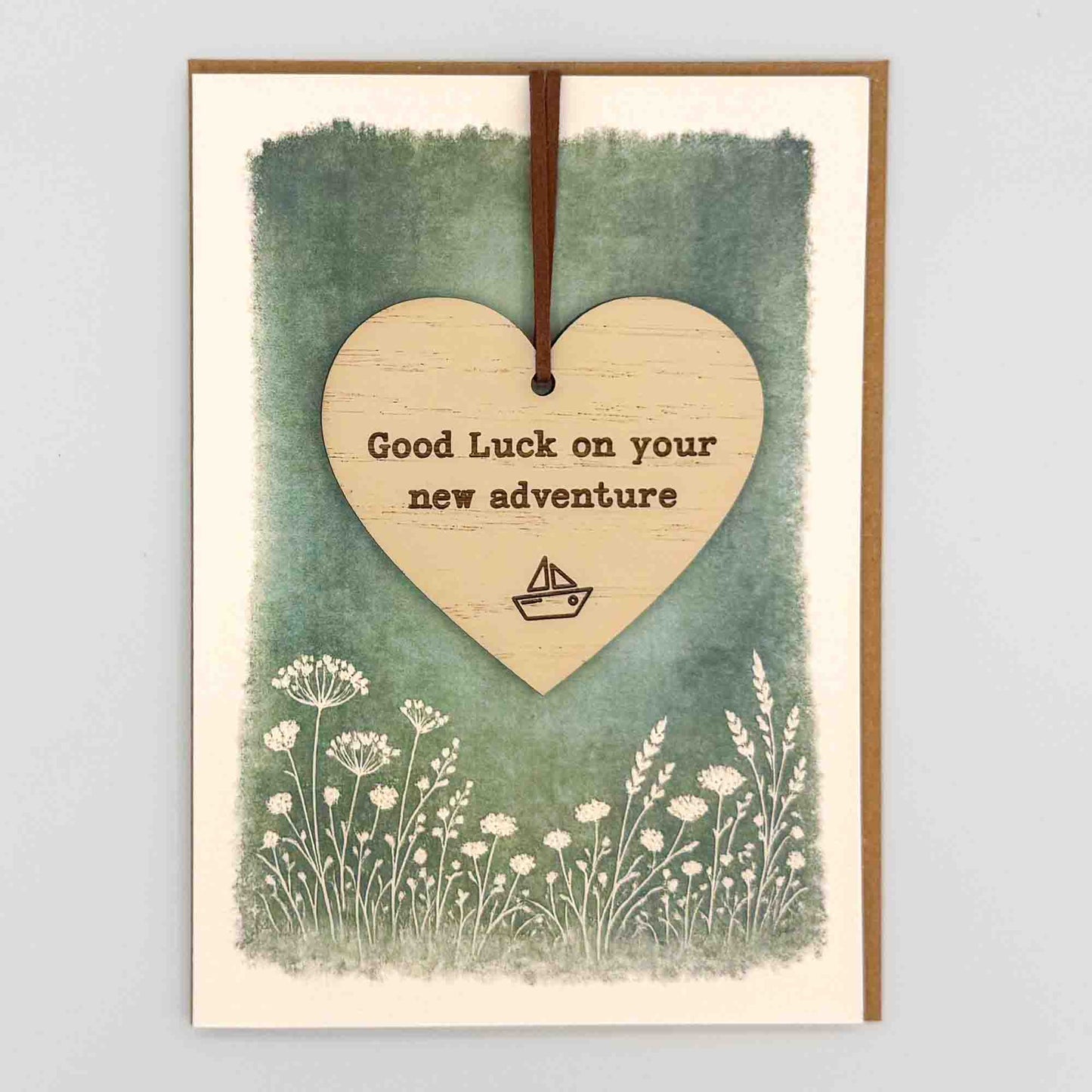 Good luck new adventure boat heart keepsake card from Sprinkled with Magic, featuring a removable wooden heart keepsake, boat icon, green botanical design and recycled kraft envelope.