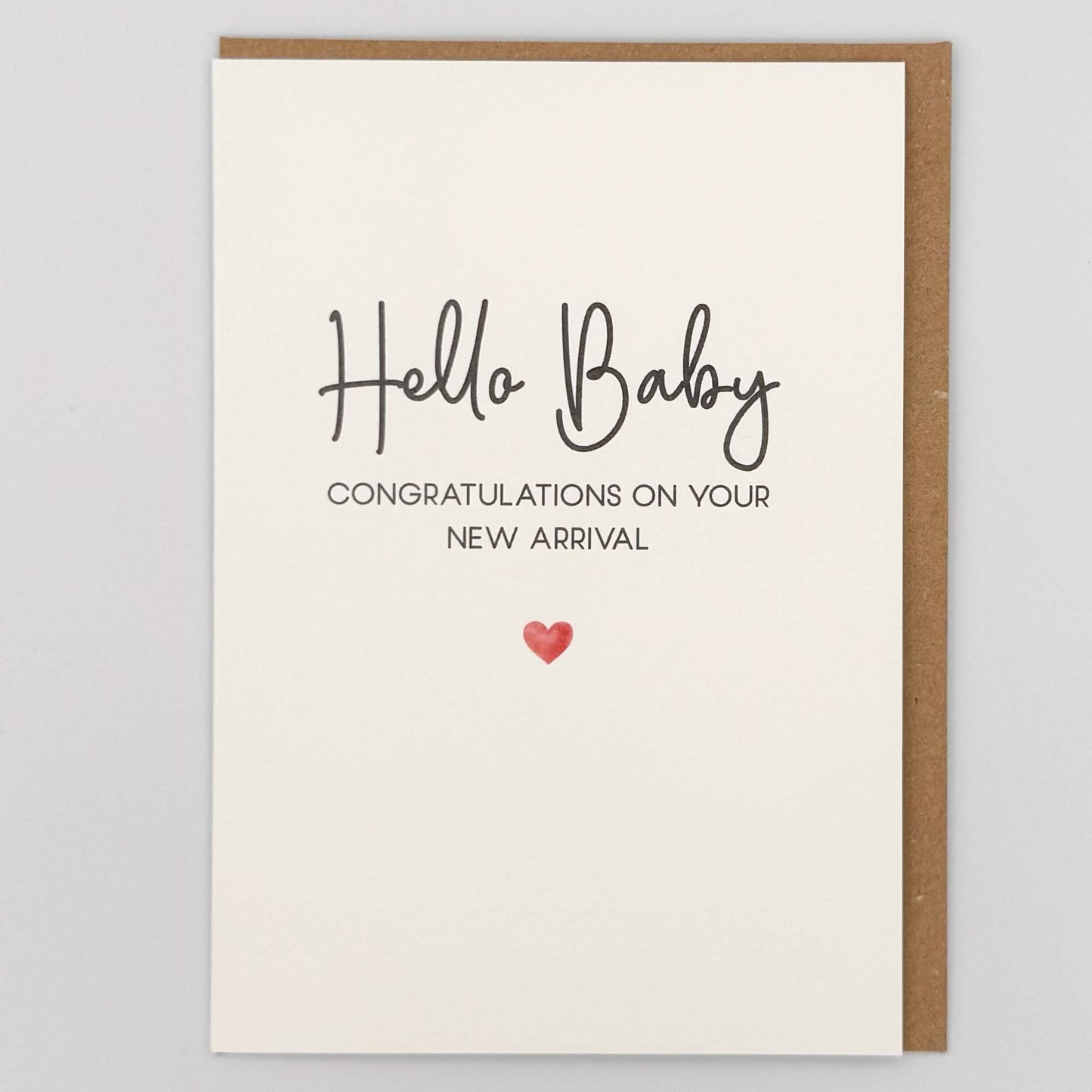 Hello baby new arrival card from Sprinkled with Magic, featuring handwritten-style wording, new baby congratulations message, a small red heart and recycled kraft envelope.