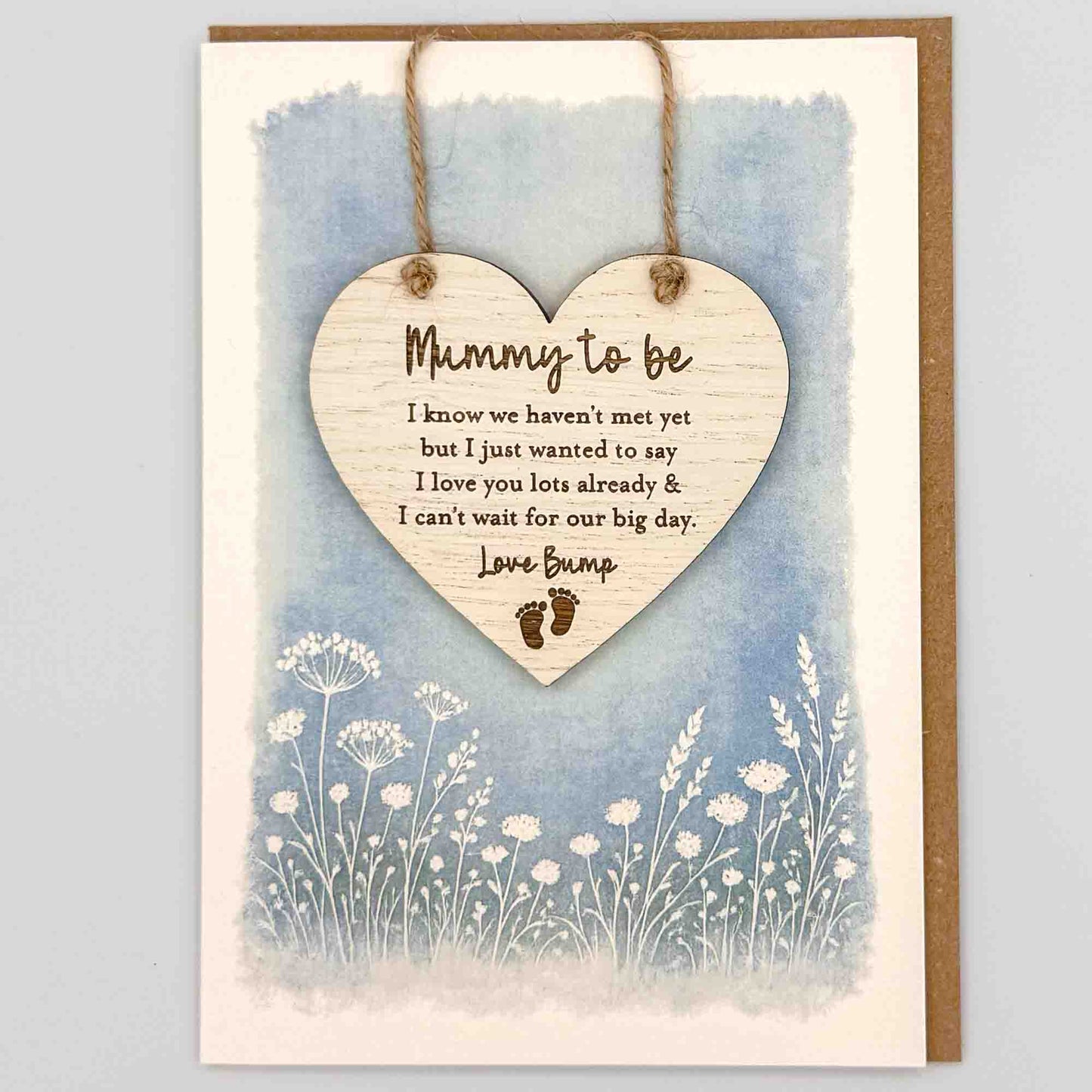 Mummy to be love bump heart keepsake card from Sprinkled with Magic, featuring a removable wooden heart keepsake, baby feet detail, blue botanical design and recycled kraft envelope.