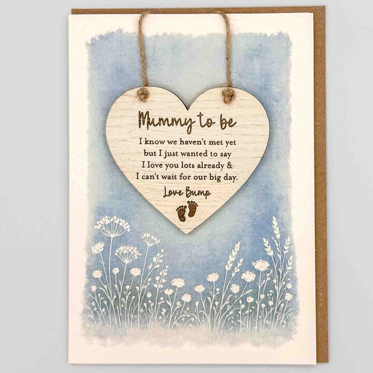 Mummy to be love bump heart keepsake card from Sprinkled with Magic, featuring a removable wooden heart keepsake, baby feet detail, blue botanical design and recycled kraft envelope.