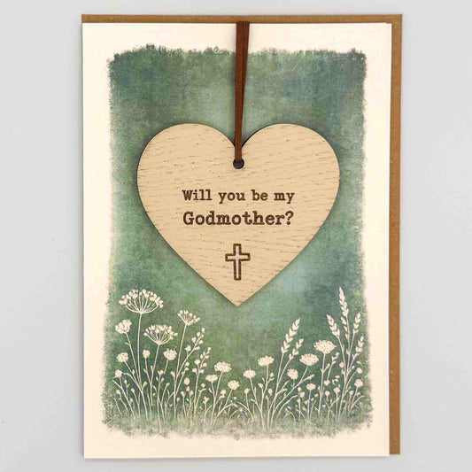 Godmother proposal cross heart keepsake card from Sprinkled with Magic, featuring a removable wooden heart keepsake, small cross detail, green botanical design and recycled kraft envelope.