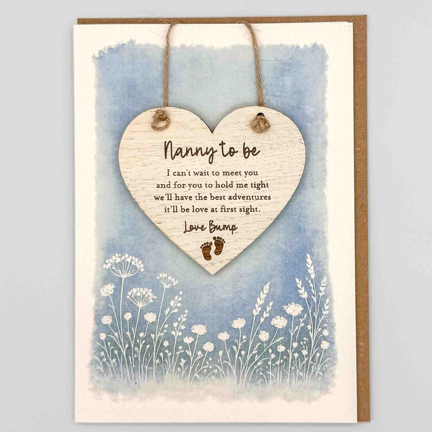 Nanny to be love bump heart keepsake card from Sprinkled with Magic, featuring a removable wooden heart keepsake, baby feet detail, blue botanical design and recycled kraft envelope.