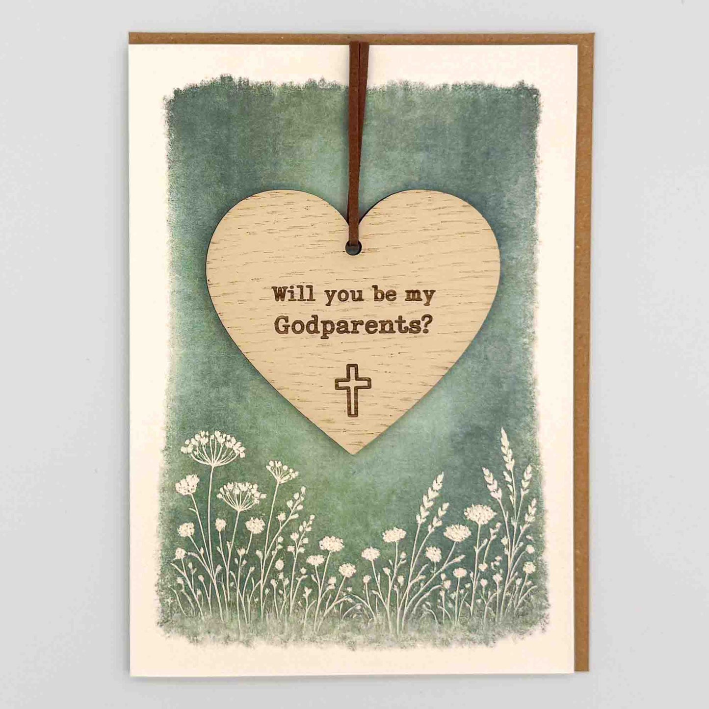 Godparents proposal cross heart keepsake card from Sprinkled with Magic, featuring a removable wooden heart keepsake, small cross detail, green botanical design and recycled kraft envelope.
