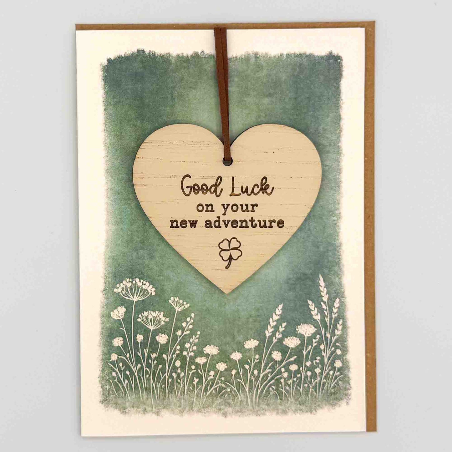 Good luck new adventure clover heart keepsake card from Sprinkled with Magic, featuring a removable wooden heart keepsake, clover icon, green botanical design and recycled kraft envelope.