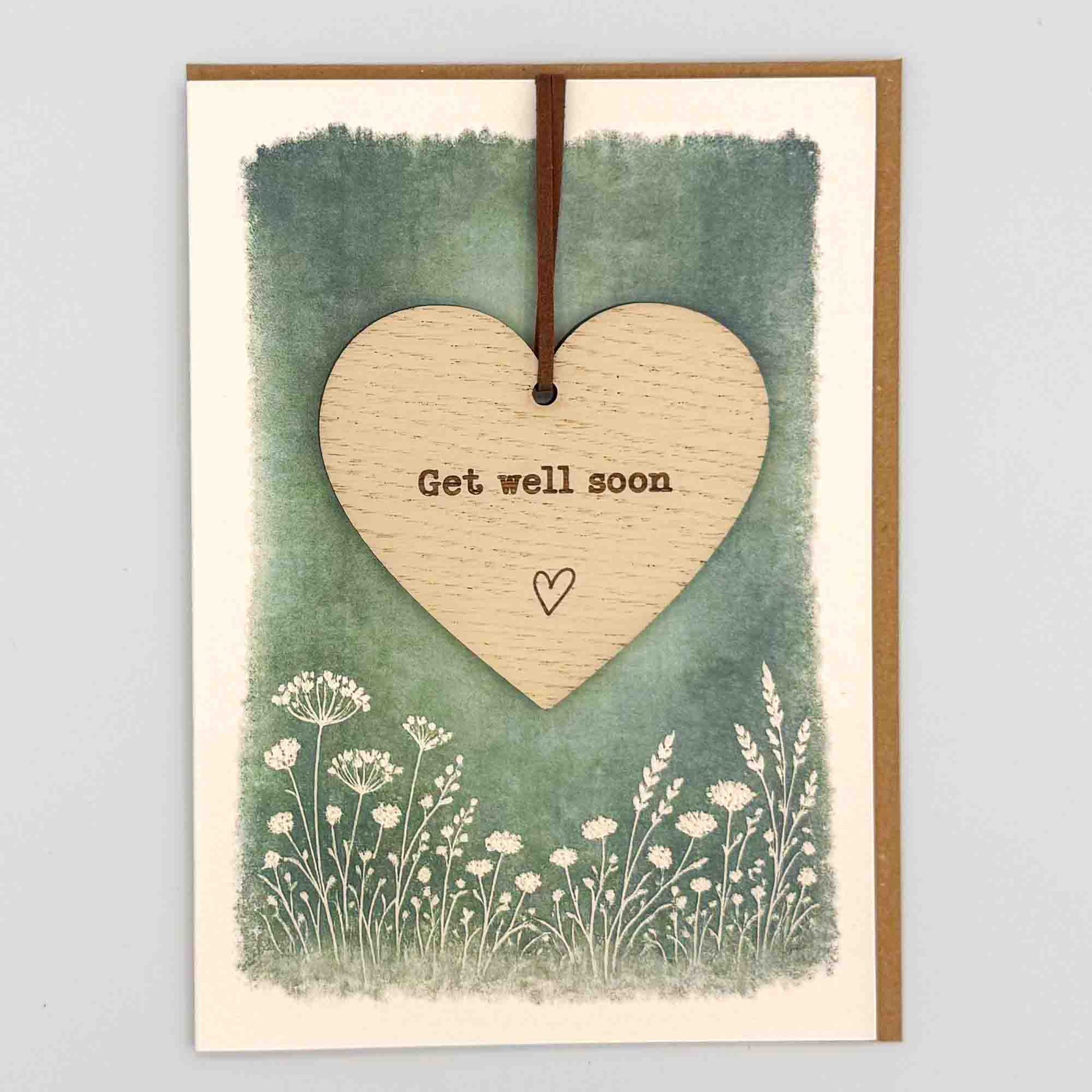 Get well soon heart keepsake card from Sprinkled with Magic, featuring a removable wooden heart keepsake, small heart detail, green botanical design and recycled kraft envelope.