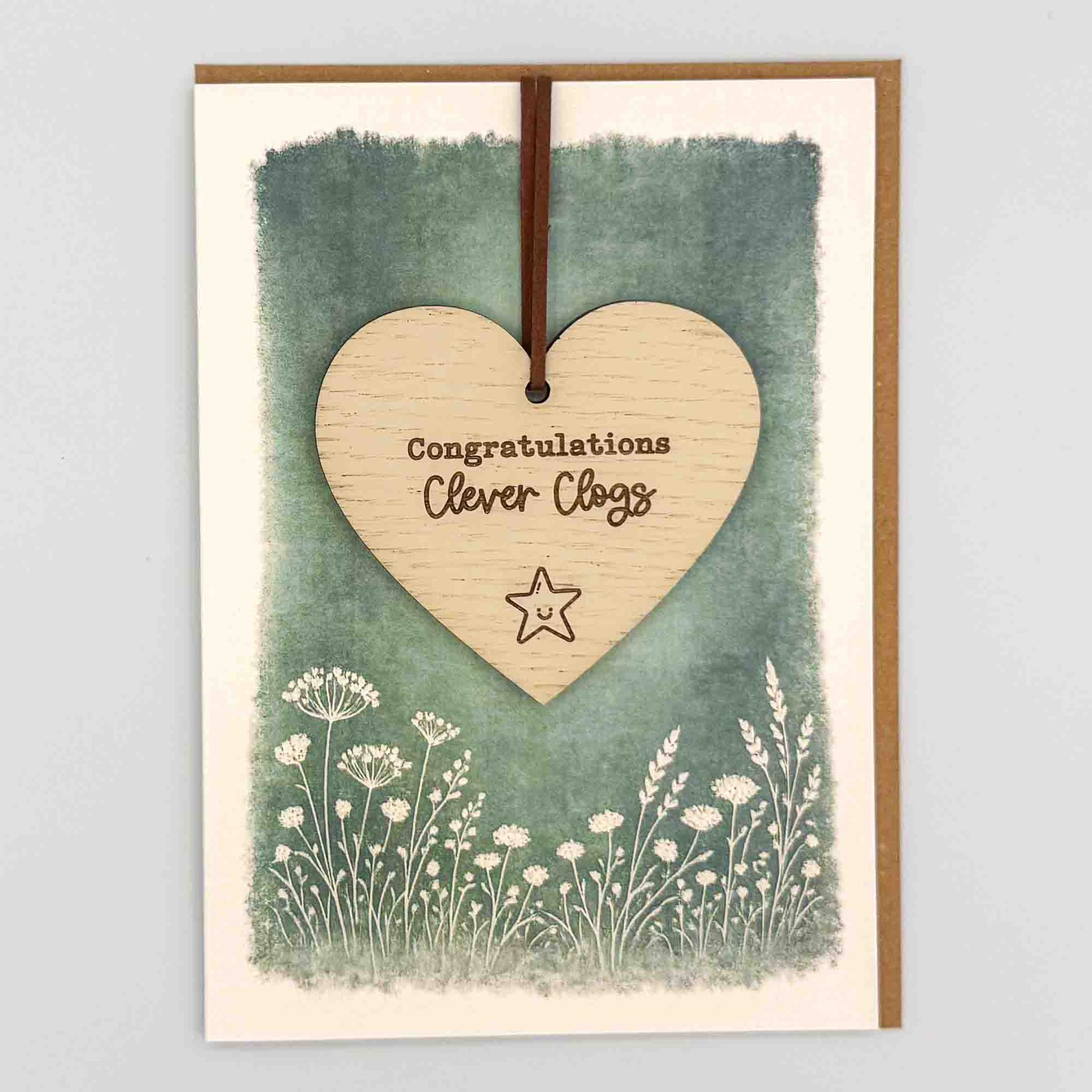 Congratulations clever clogs star heart keepsake card from Sprinkled with Magic, featuring a removable wooden heart keepsake, small star detail, green botanical design and recycled kraft envelope.