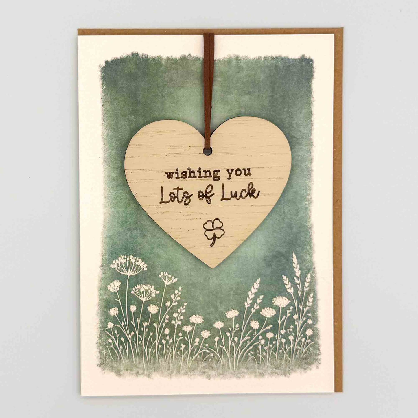 Lots of luck heart keepsake card from Sprinkled with Magic, featuring a removable wooden heart keepsake, clover detail, green botanical design and recycled kraft envelope.