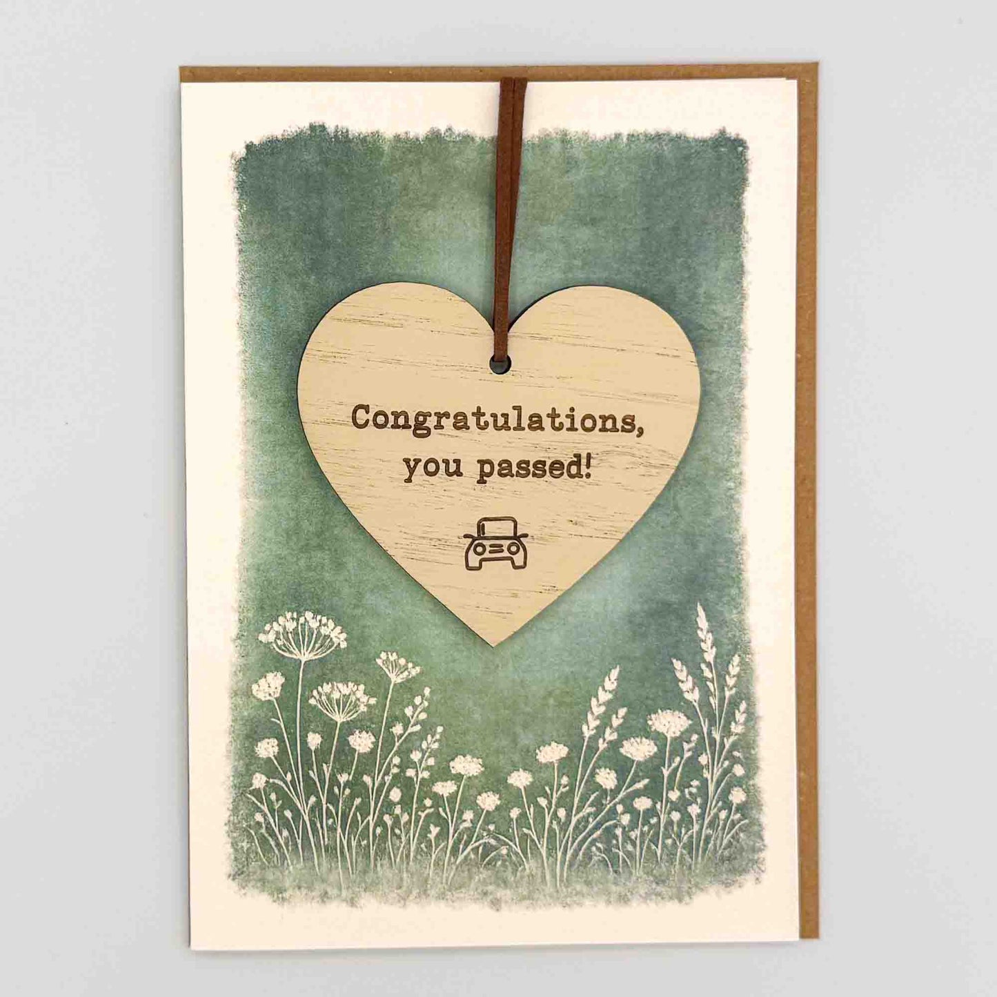 Congratulations you passed car heart keepsake card from Sprinkled with Magic, featuring a removable wooden heart keepsake, small car detail, green botanical design and recycled kraft envelope.