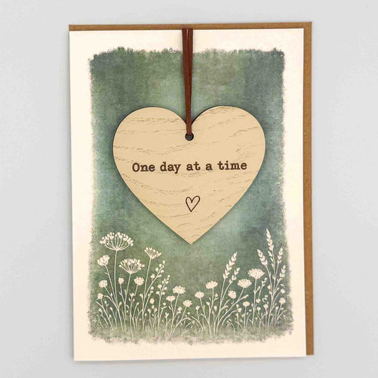 One day at a time heart keepsake card from Sprinkled with Magic, featuring a removable wooden heart keepsake, green botanical design and recycled kraft envelope.