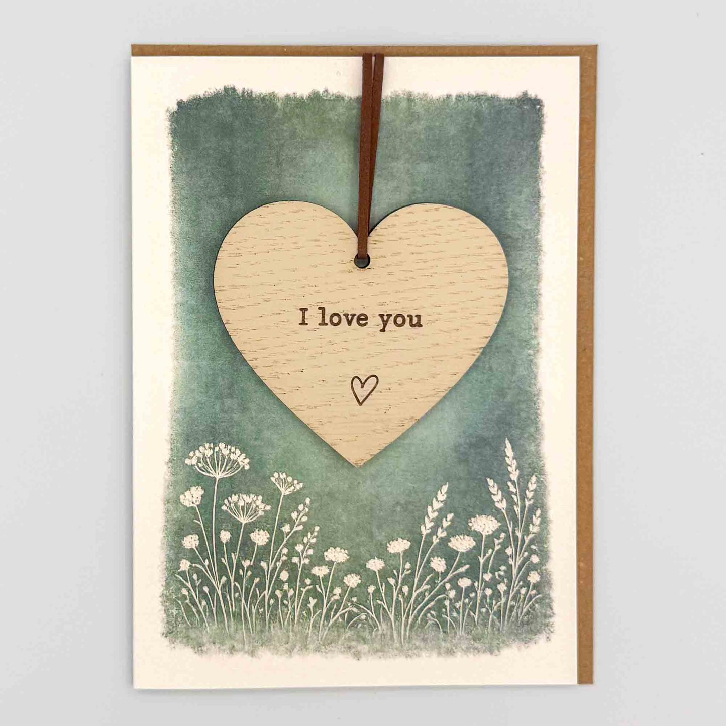 I love you heart keepsake card from Sprinkled with Magic, featuring a removable wooden heart keepsake, green botanical design and recycled kraft envelope.