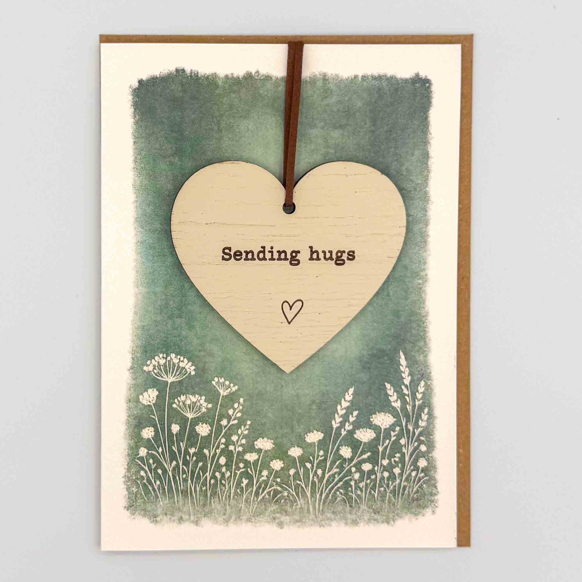 Sending hugs heart keepsake card from Sprinkled with Magic, featuring a removable wooden heart keepsake, green botanical design and recycled kraft envelope.