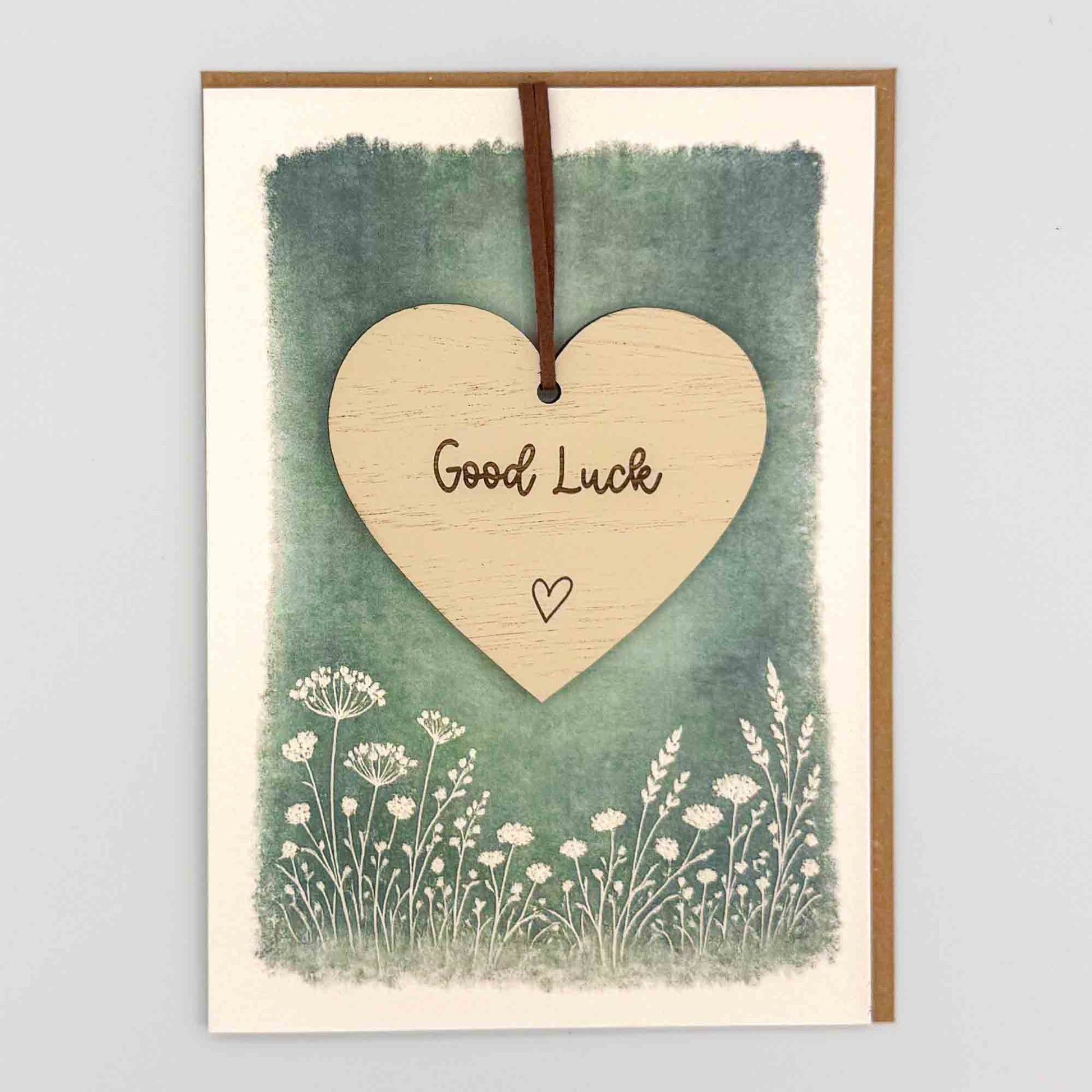 Good luck heart keepsake card from Sprinkled with Magic, featuring a removable wooden heart keepsake, small heart detail, green botanical design and recycled kraft envelope.
