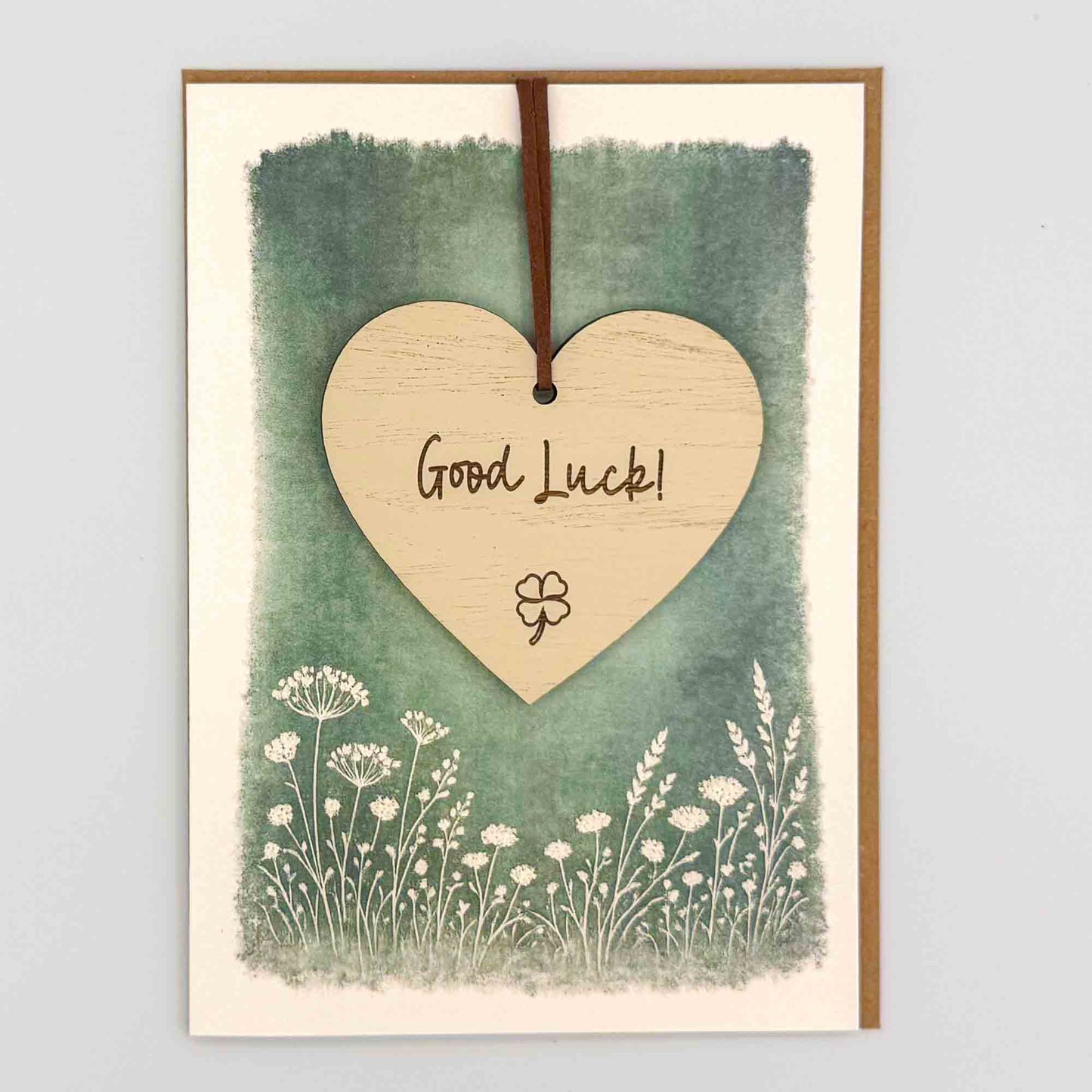 Good luck clover heart keepsake card from Sprinkled with Magic, featuring a removable wooden heart keepsake, small clover detail, green botanical design and recycled kraft envelope.
