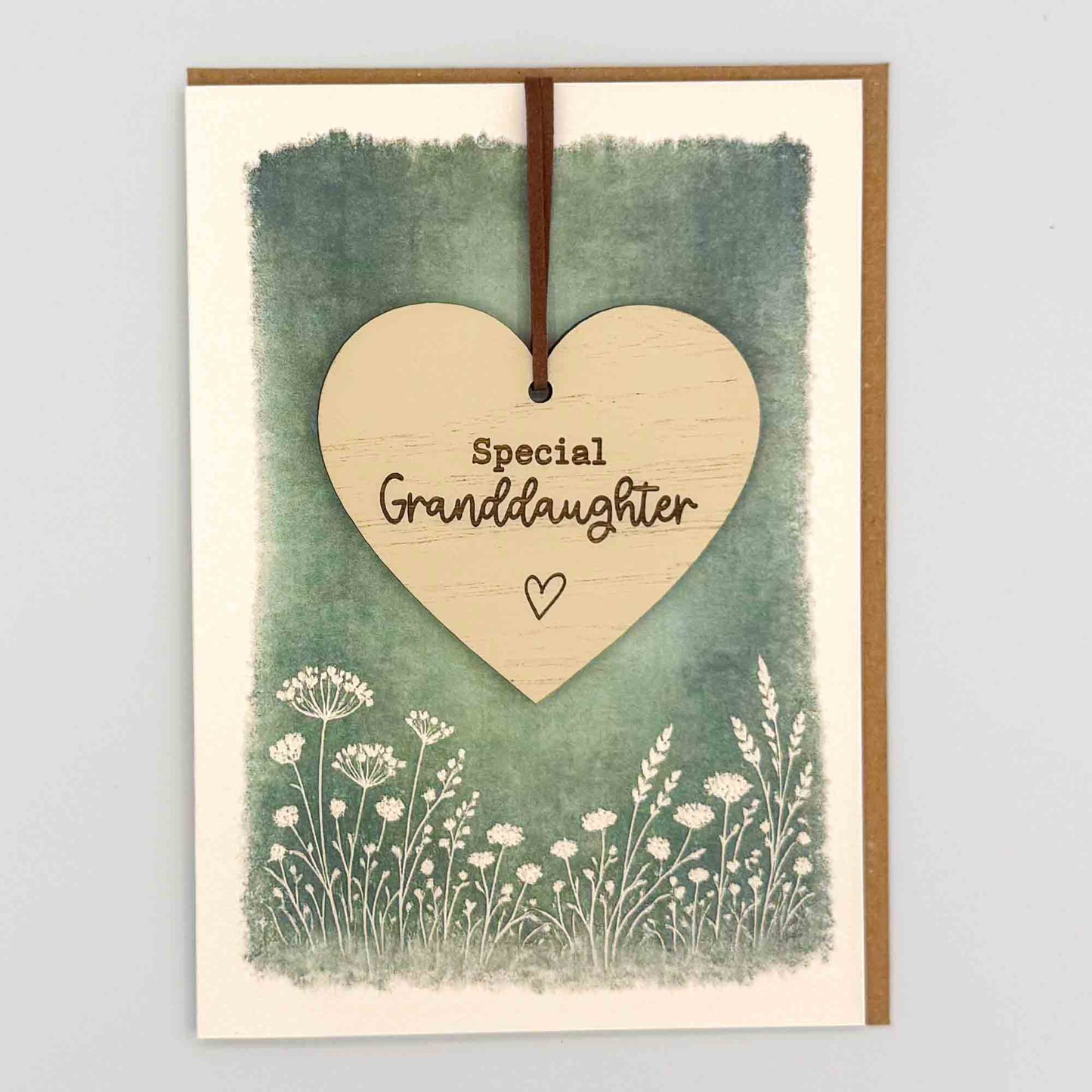 Special granddaughter heart keepsake card from Sprinkled with Magic, featuring a removable wooden heart keepsake, green botanical design and recycled kraft envelope.