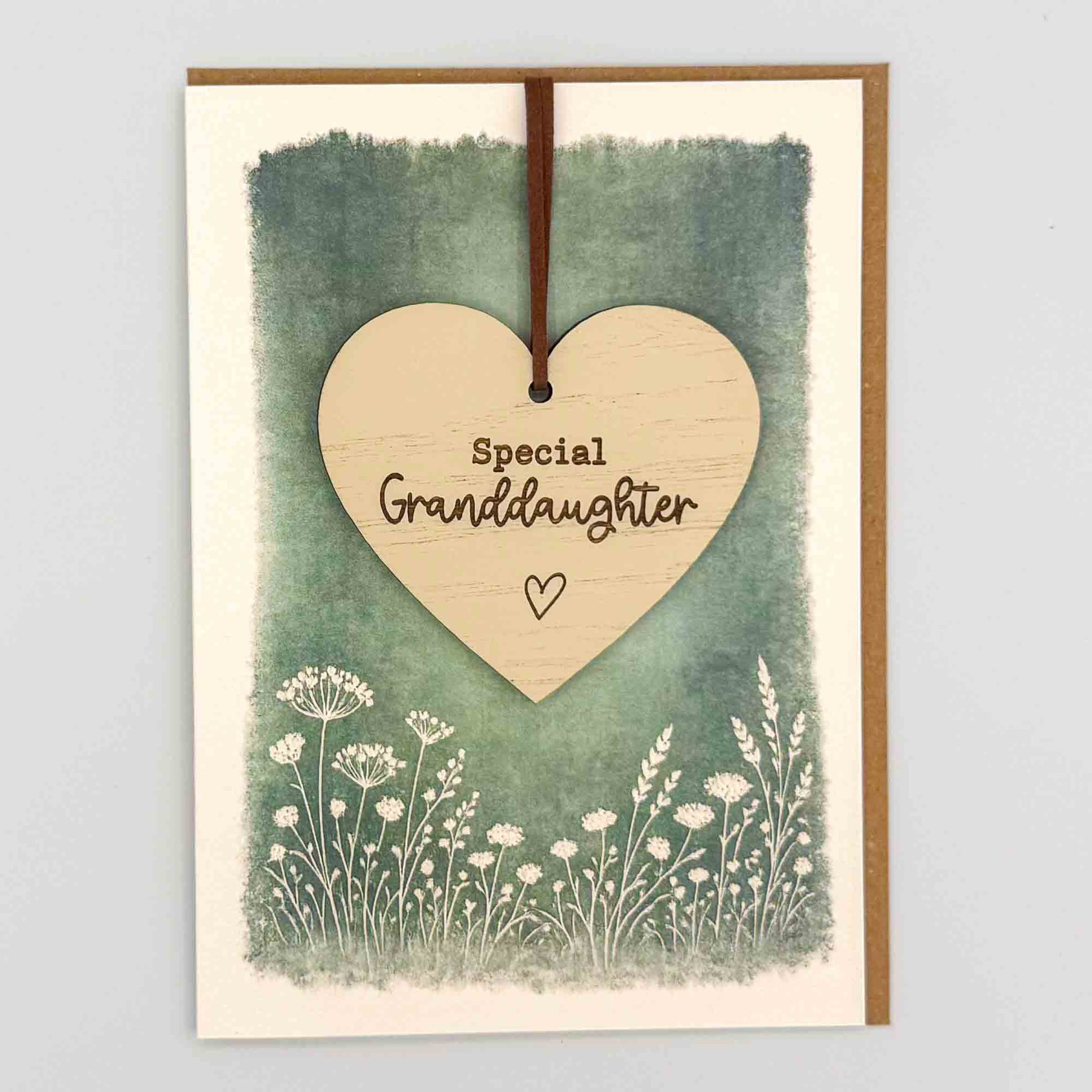 Special granddaughter heart keepsake card from Sprinkled with Magic, featuring a removable wooden heart keepsake, green botanical design and recycled kraft envelope.