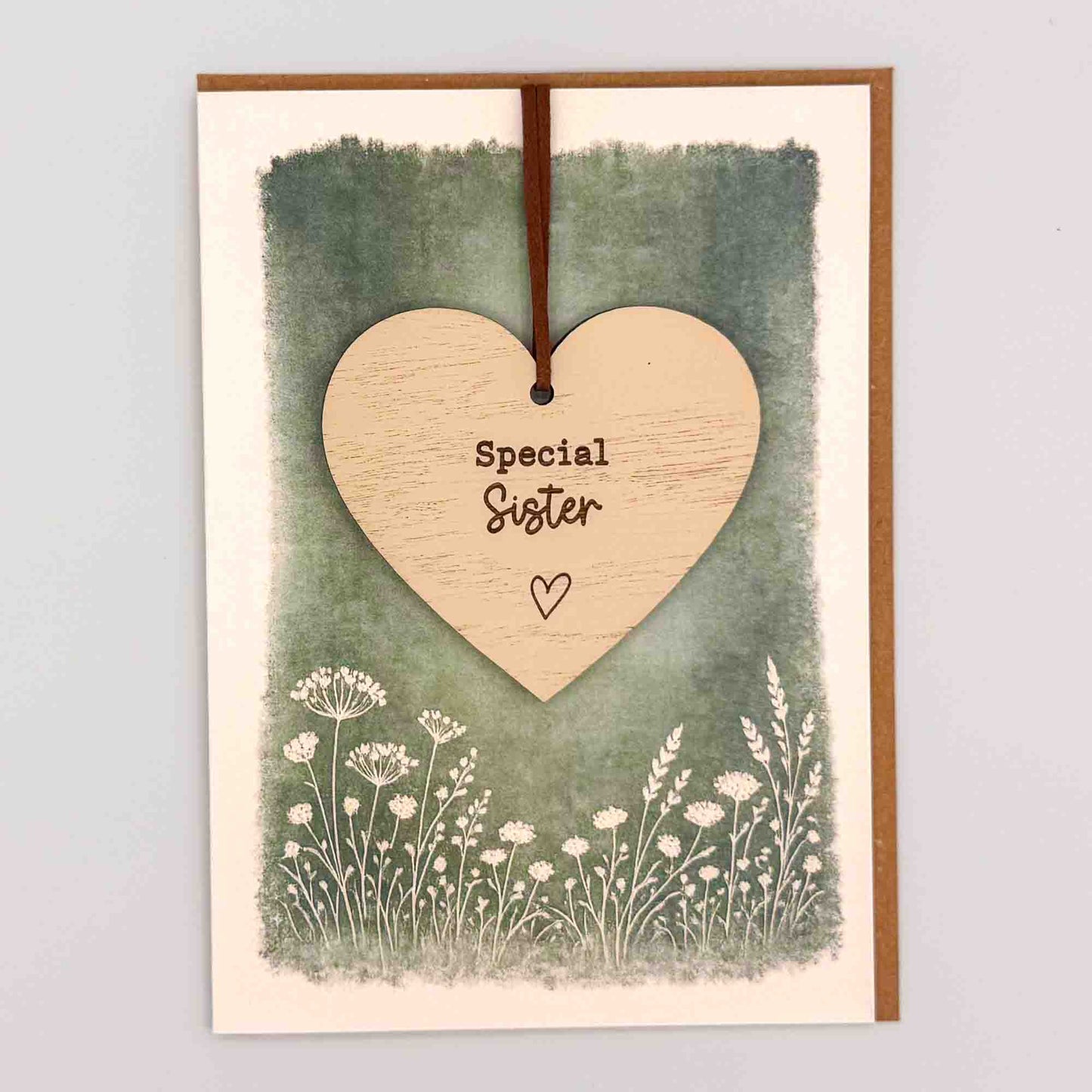 Special sister heart keepsake card from Sprinkled with Magic, featuring a removable wooden heart keepsake, green botanical design and recycled kraft envelope.