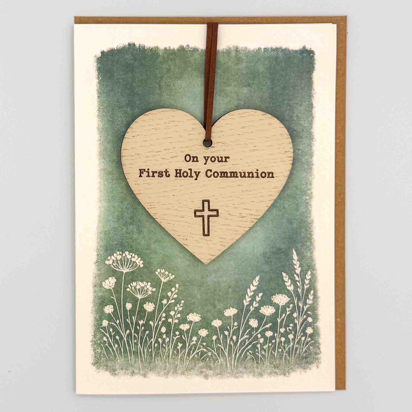 First Holy Communion heart keepsake card from Sprinkled with Magic, featuring a removable wooden heart keepsake, cross detail, green botanical design and recycled kraft envelope.