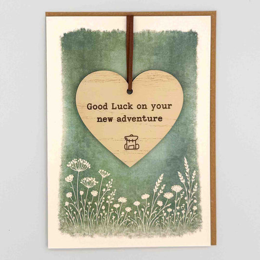 Good luck new adventure heart keepsake card from Sprinkled with Magic, featuring a removable wooden heart keepsake, rucksack icon, green botanical design and recycled kraft envelope.