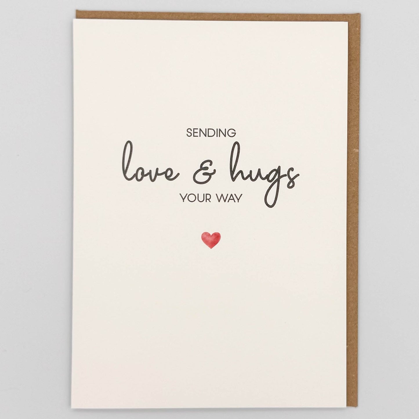 Sending love and hugs card from Sprinkled with Magic, featuring handwritten-style wording, a small red heart and recycled kraft envelope.