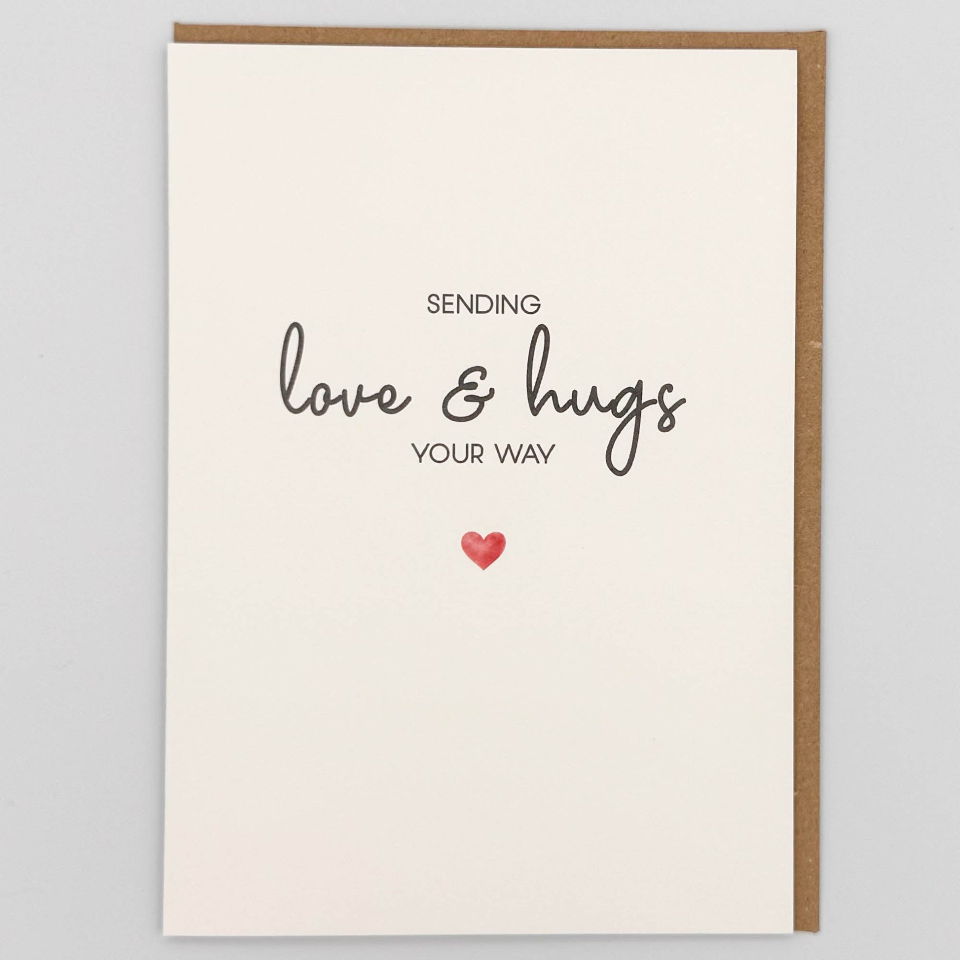 Sending love and hugs card from Sprinkled with Magic, featuring handwritten-style wording, a small red heart and recycled kraft envelope.