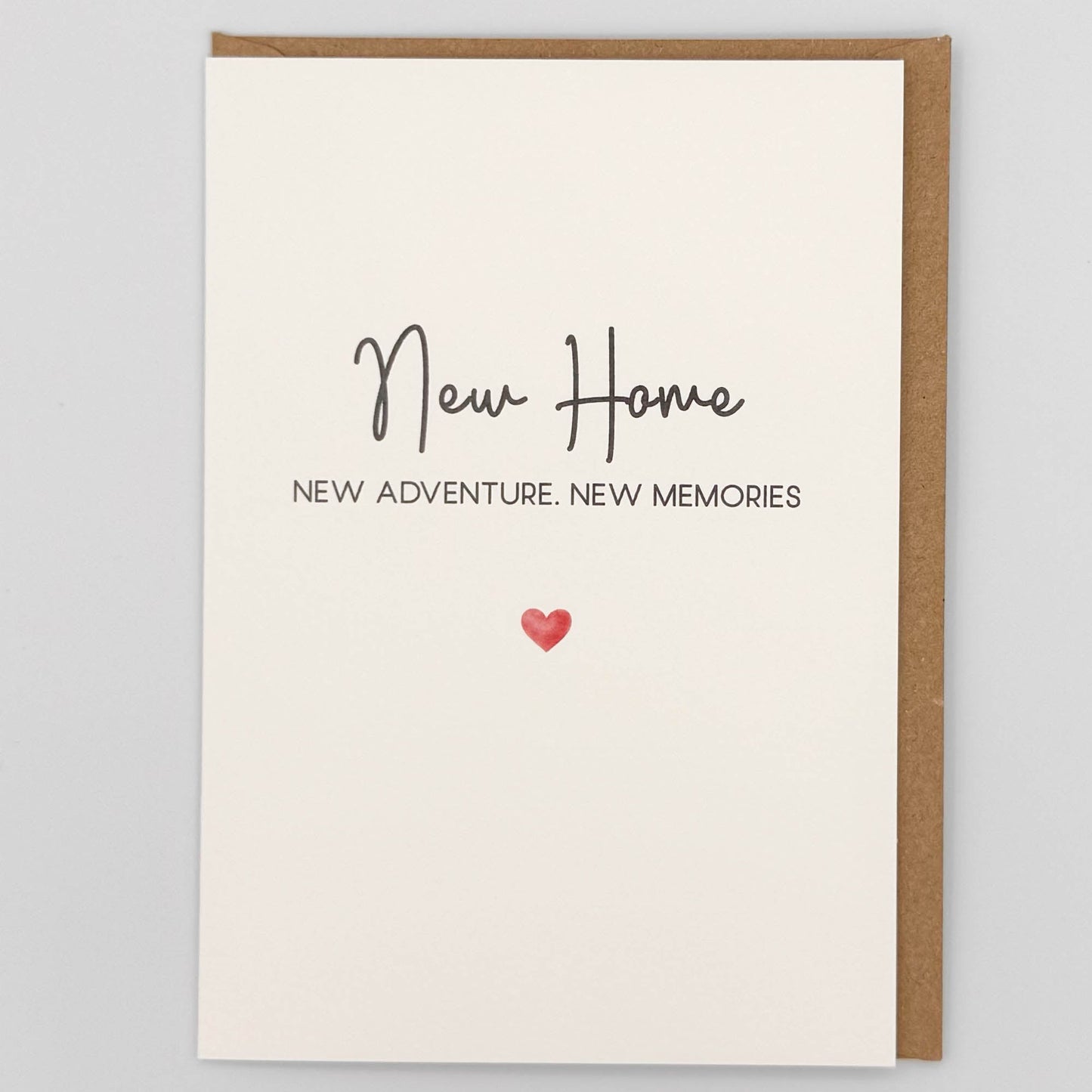New home card from Sprinkled with Magic, featuring handwritten-style new home wording, a small red heart and recycled kraft envelope.