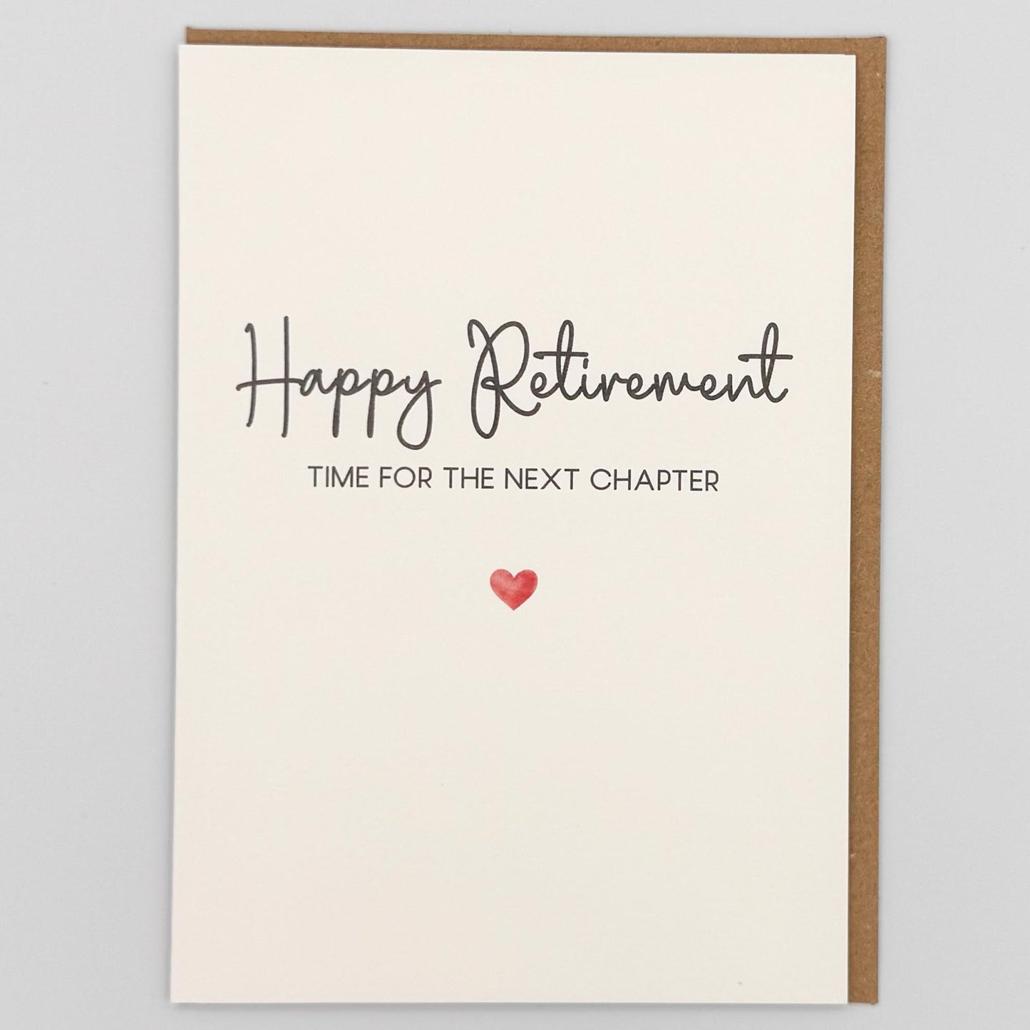 Happy retirement next chapter card from Sprinkled with Magic, featuring handwritten-style retirement wording, a small red heart and recycled kraft envelope.