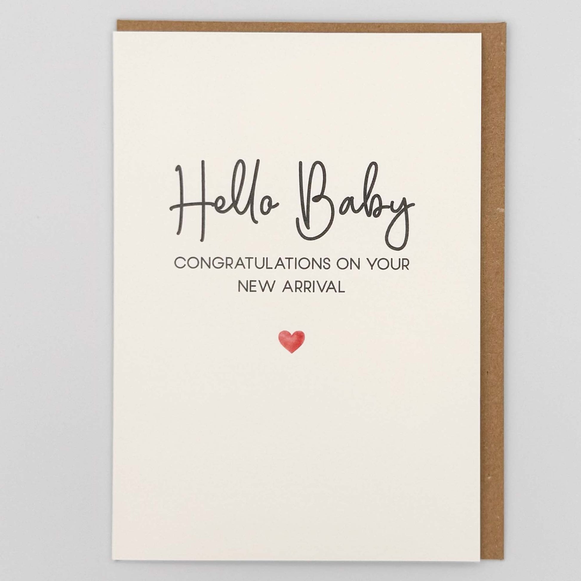 Hello baby new arrival card from Sprinkled with Magic, featuring handwritten-style wording, new baby congratulations message, a small red heart and recycled kraft envelope.